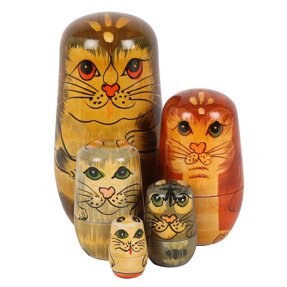 Set of five handpainted wooden cat Russian dolls arranged from largest to smallest on a white background