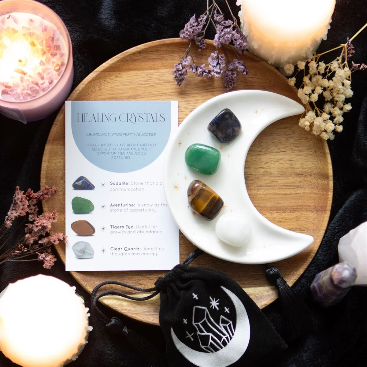 Healing crystal set with four tumblestones and crescent moon trinket dish on white background