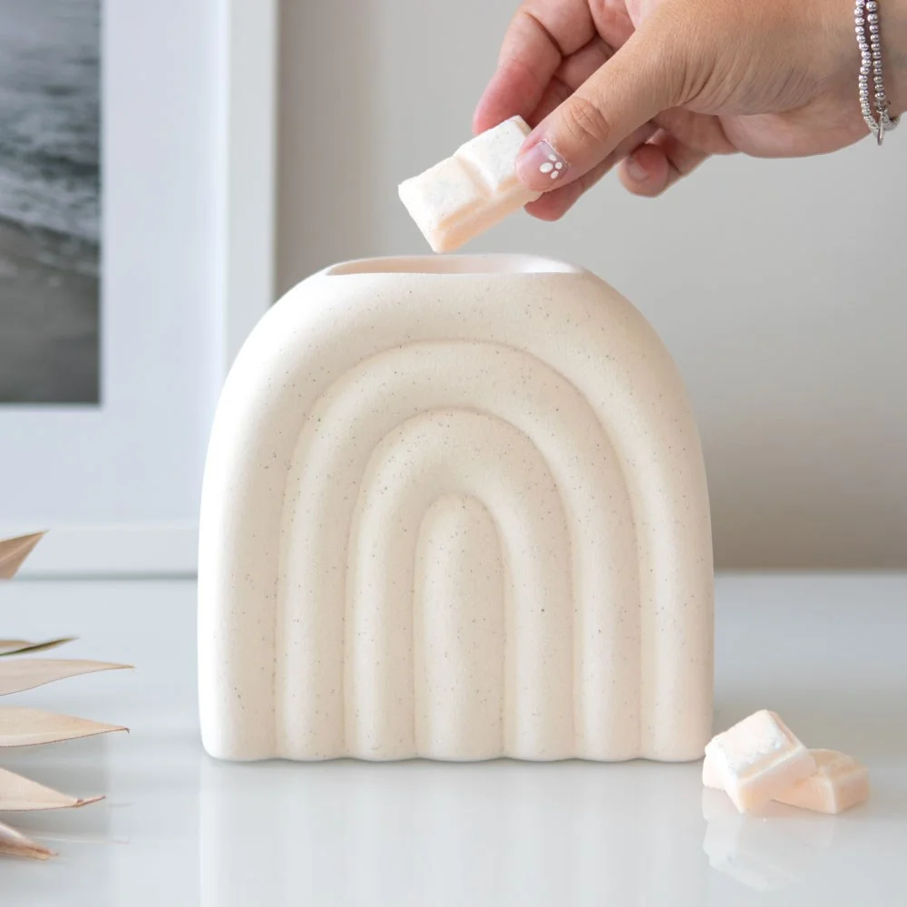 Cream oil burner with speckled finish and arched design made from dolomite on a white background