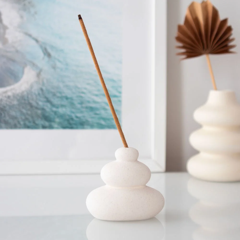 Cream speckle balancing stone incense holder shaped like stacked stones with a single incense stick inserted