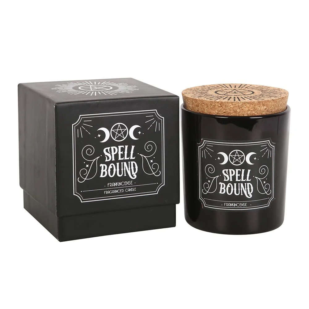 Lit Spell Bound frankincense scented candle in a clear glass jar with warm glowing flame and dark background