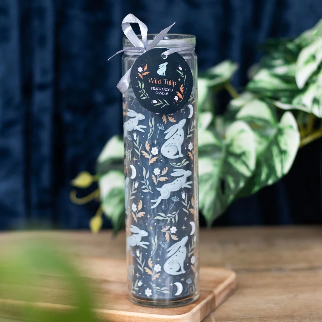 Tall tube candle with wild tulip scent, decorated with mystical hares and moon design on white background