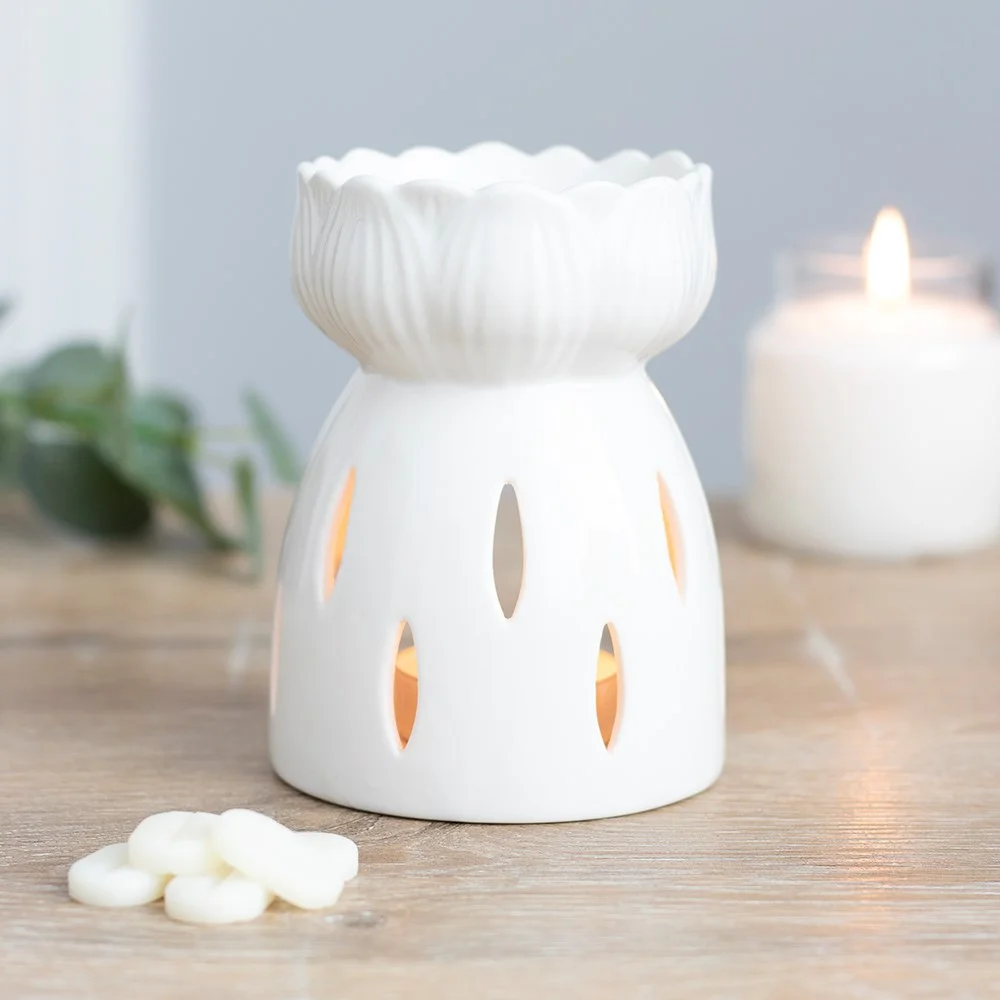 White ceramic oil burner with lotus flower design and cut-out details highlighting warm candle glow