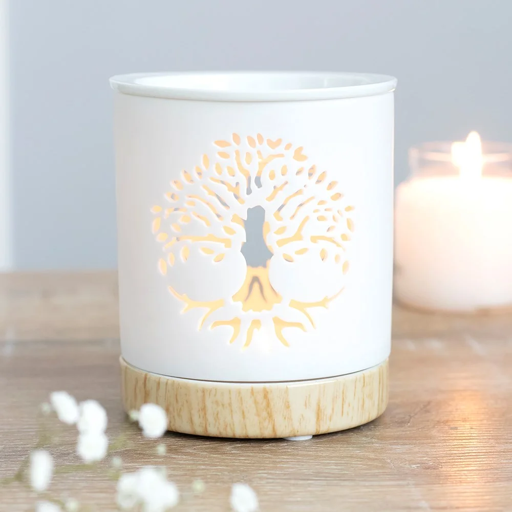 White ceramic oil burner featuring a cut‑out Tree of Life, wood‑effect base, built‑in dish for oil, a tealight inside.