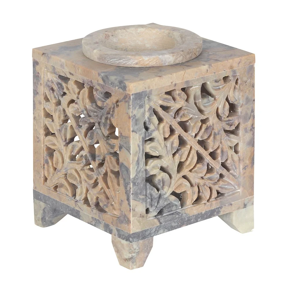 Soapstone oil burner with Moroccan arch cutout and leafy design, holding a lit tealight inside, 10cm tall