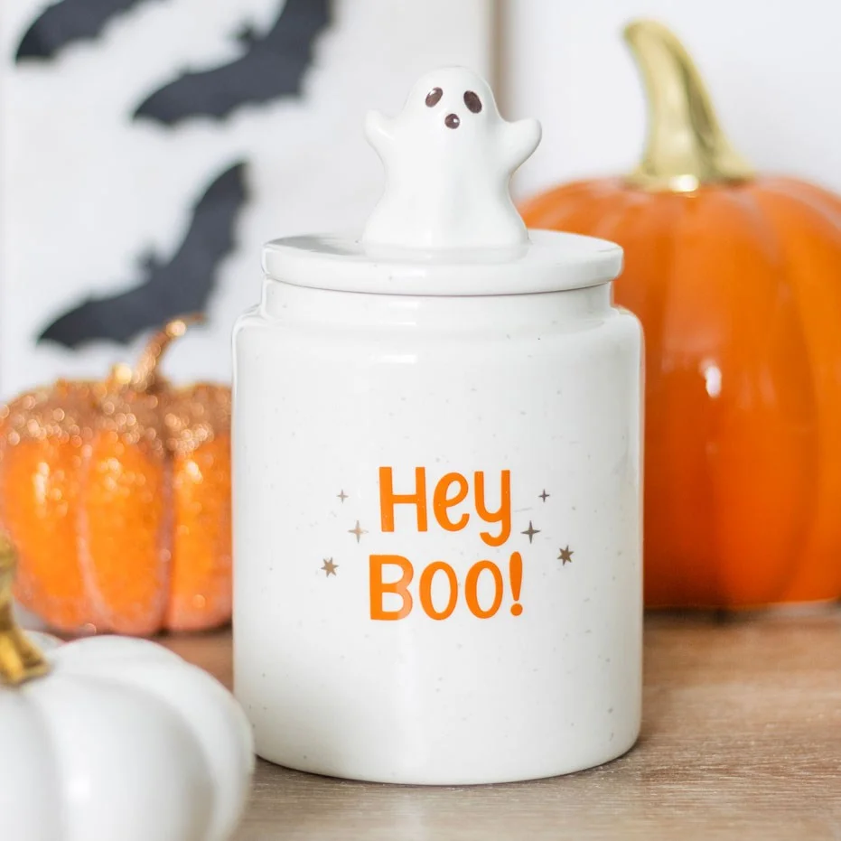 Ceramic Halloween storage jar with orange "Hey boo!" text on white speckled background and ghost-shaped lid handle