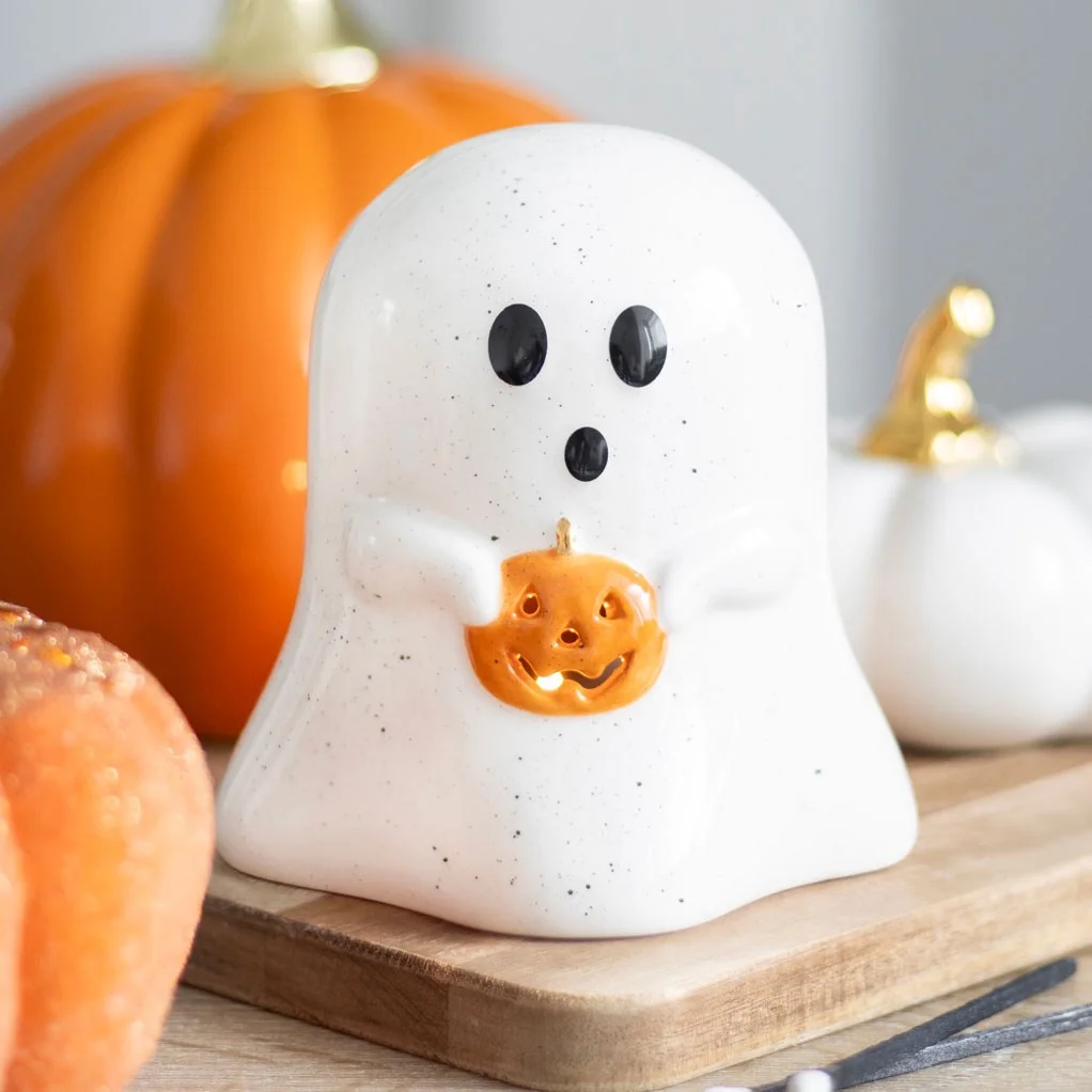 Ghost tealight holder shaped like a smiling ghost with a small pumpkin, 11cm tall, holding a lit tealight candle
