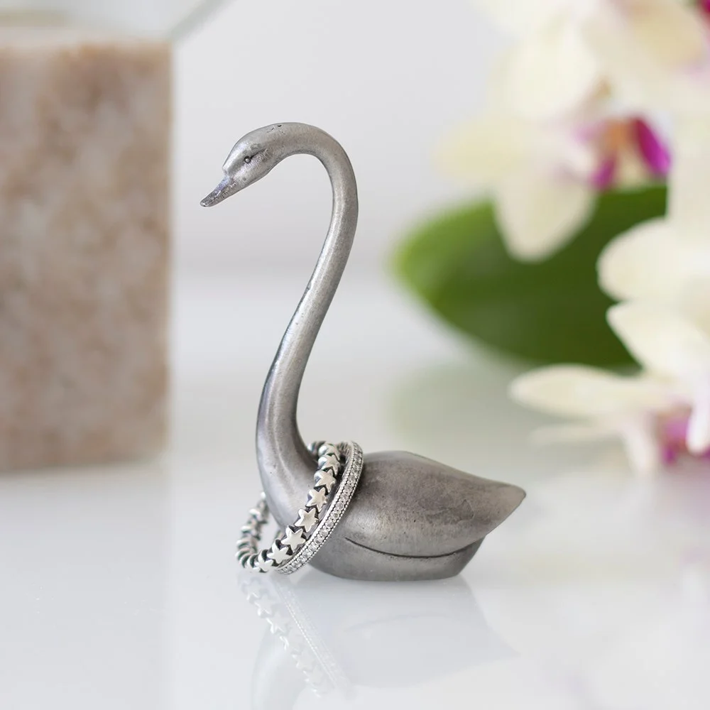 Elegant metal swan ring holder in iron, 6.5cm tall, displayed on a dressing table with rings on its neck