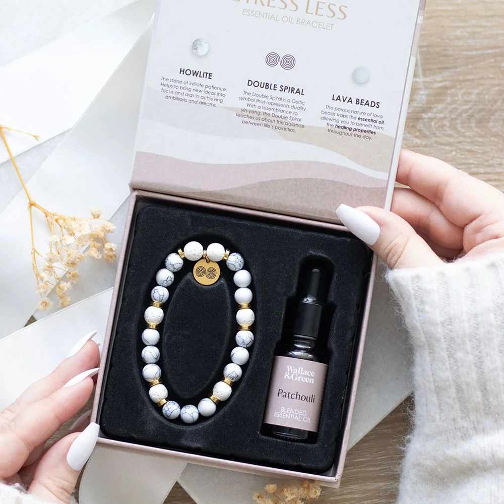 Howlite crystal bracelet with lava beads and double spiral charm, shown with patchouli essential oil bottle in gift box