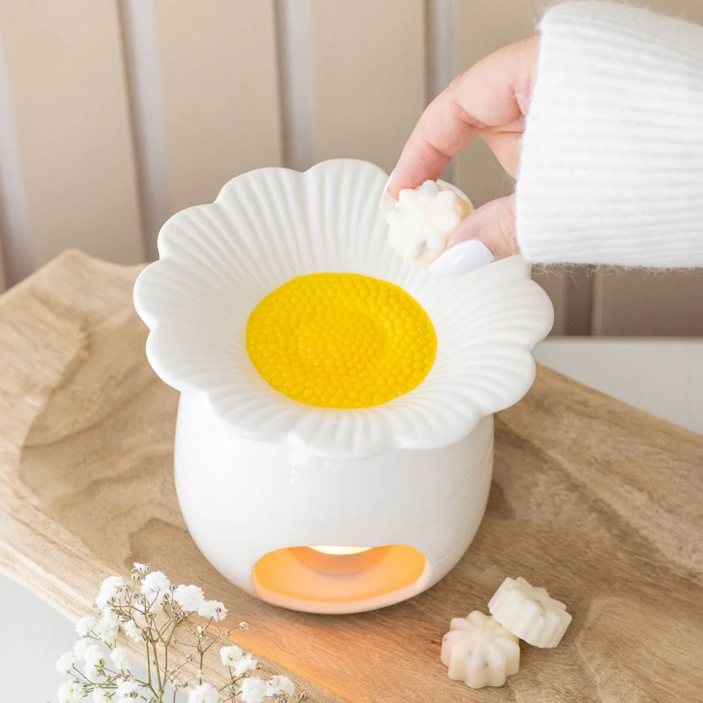 White ceramic daisy shaped oil burner with a hollow centre for tealight or wax melts on a plain background