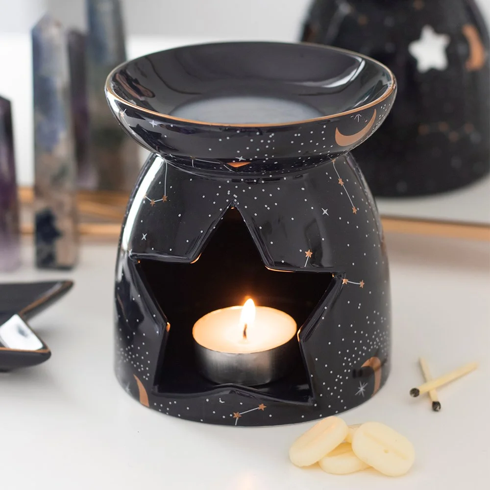 Purple oil burner with gold constellation design and star-shaped tealight opening on a white background