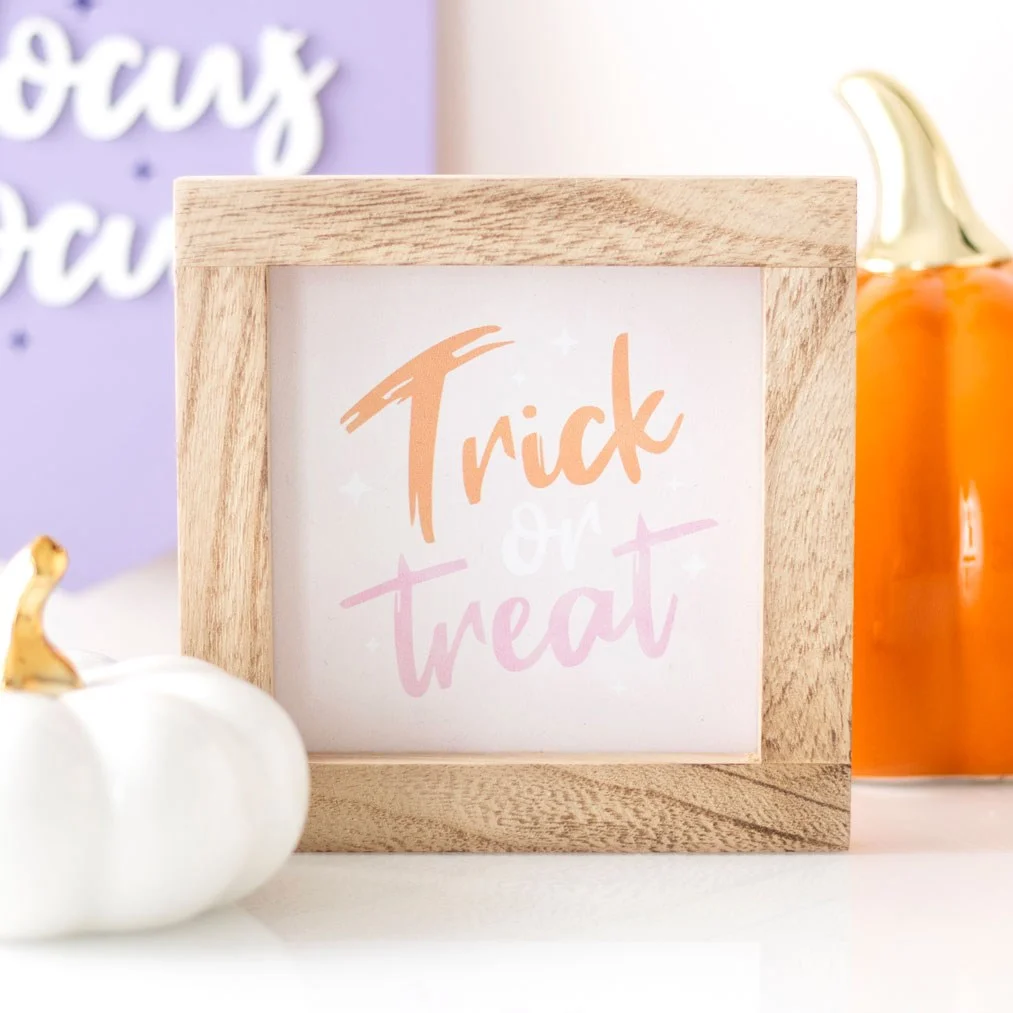 Pink Halloween sign with wooden frame featuring colorful Trick or Treat text in pink, white, and orange shades