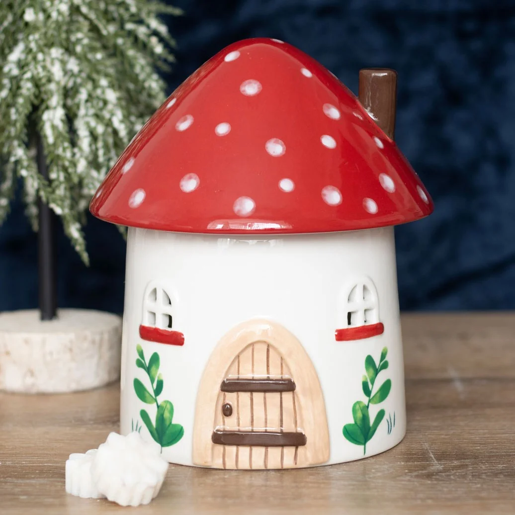 Ceramic mushroom oil burner shaped like a toadstool house with windows and a removable lid on a white background