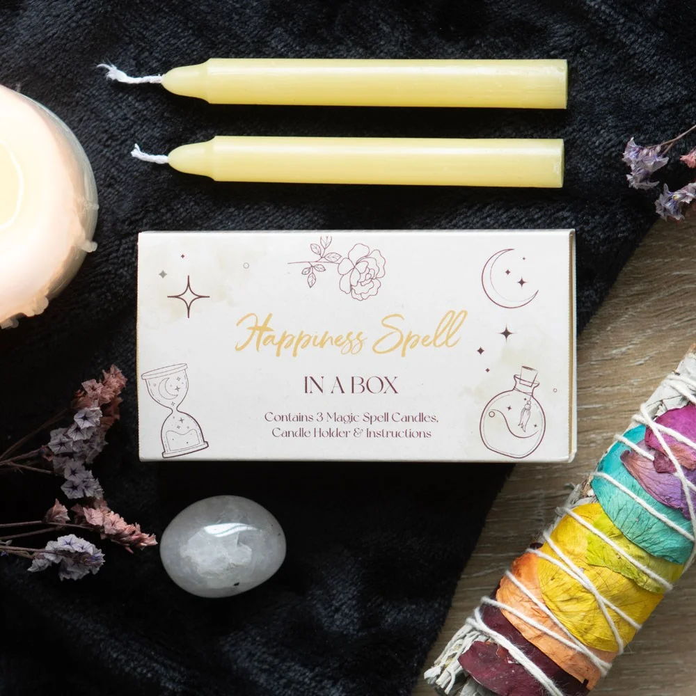 Closed sliding box with three unscented yellow candles and instructions, part of a happiness spell kit