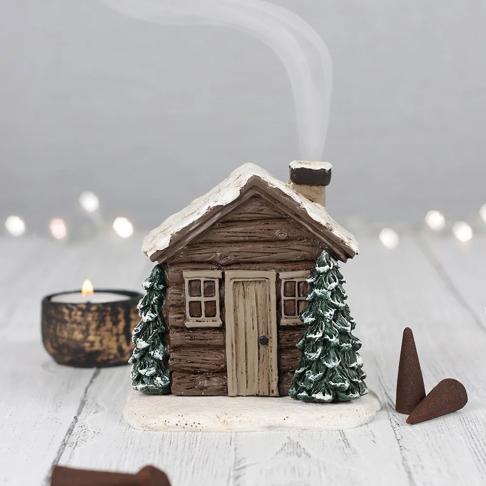 Ceramic log cabin incense burner with smoke coming from chimney, designed for use with incense cones, 10cm tall