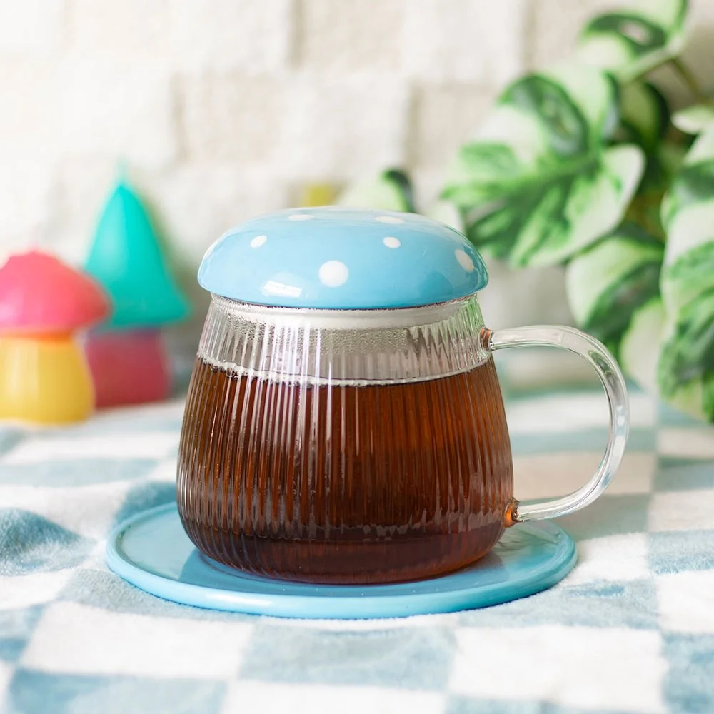 Blue glass mushroom mug with matching saucer in sky blue, holding a hot drink on a white background