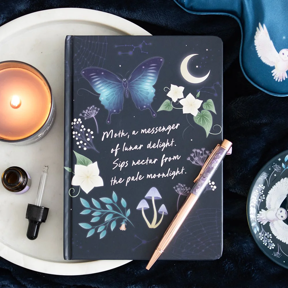 Midnight moth journal with gold foil pages, night sky and forest plant design, open to lined pages with purple ribbon marker