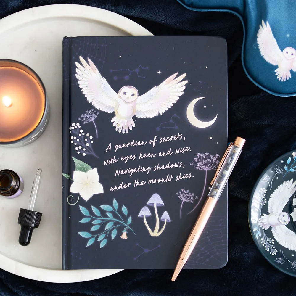 Night owl journal with flying owl design, gold foil pages, and sodalite crystal chip ballpoint pen on wooden surface