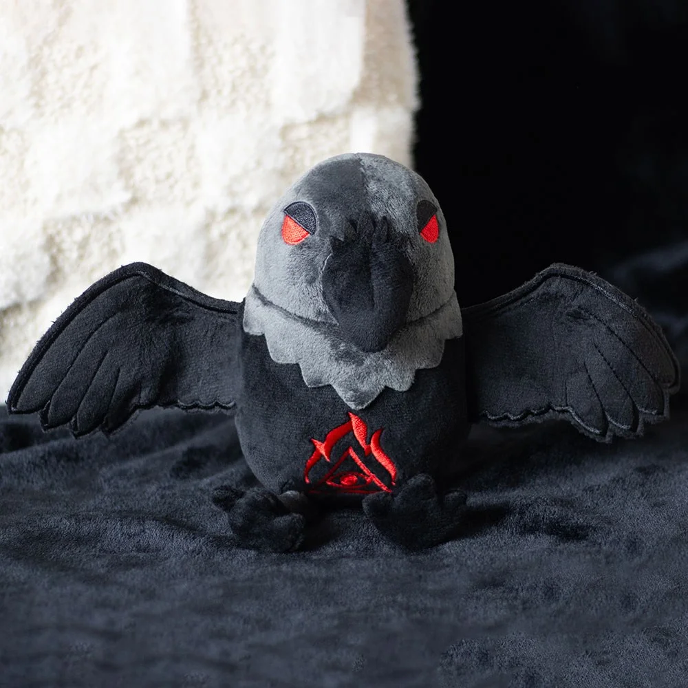 Black raven plush toy with soft wings, red embroidered eyes, and stitched all-seeing eye on chest, sitting upright