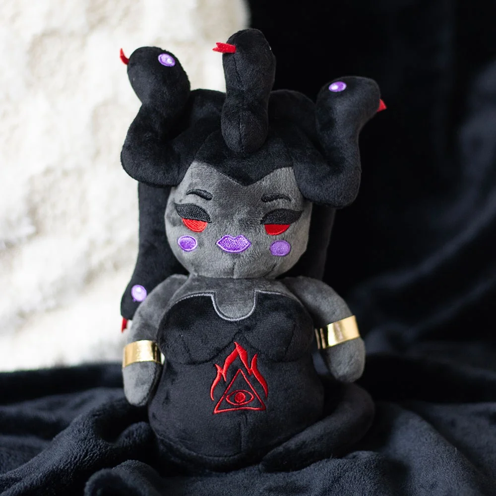 Medusa plush toy with twisted serpent hair, red embroidered eyes, all-seeing eye dress design, and metallic arm bands