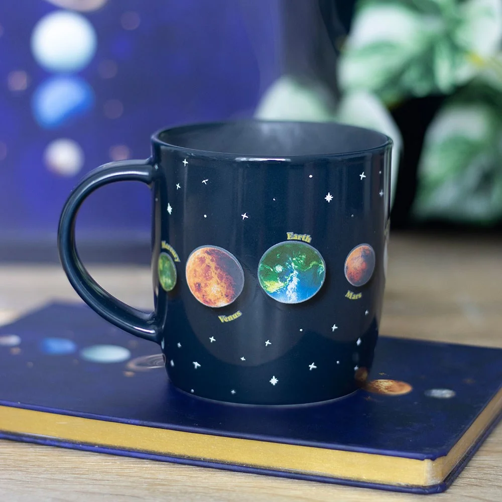 Black ceramic solar system mug showing planets and stars, heat-activated design with 500ml capacity