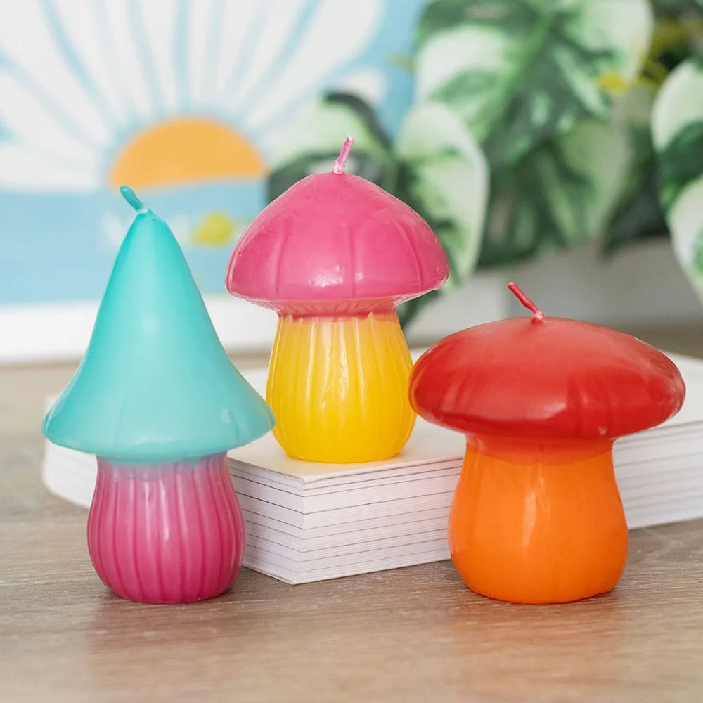 Set of 3 colorful mushroom shaped candles in varying sizes arranged on a plain white background
