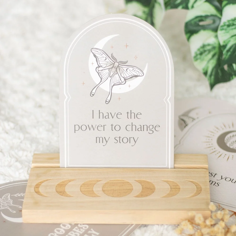 Set of 10 luna moth and crescent moon affirmation cards with motivational messages displayed on a wooden stand