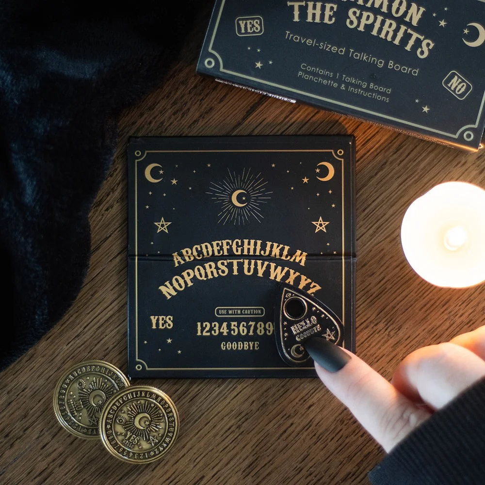 Black and gold mini talking board in a compact matchbox‑sized box, featuring a spirit board and planchette.