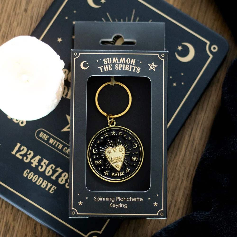 Gold-tone spinning talking board keyring planchette on a white background with matching presentation box