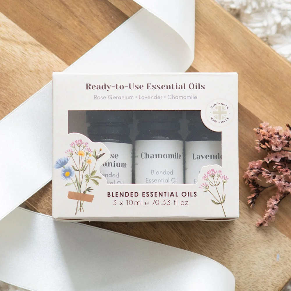 Set of three 10ml bottles of floral essential oils set with rose geranium, lavender, and chamomile blends on white background
