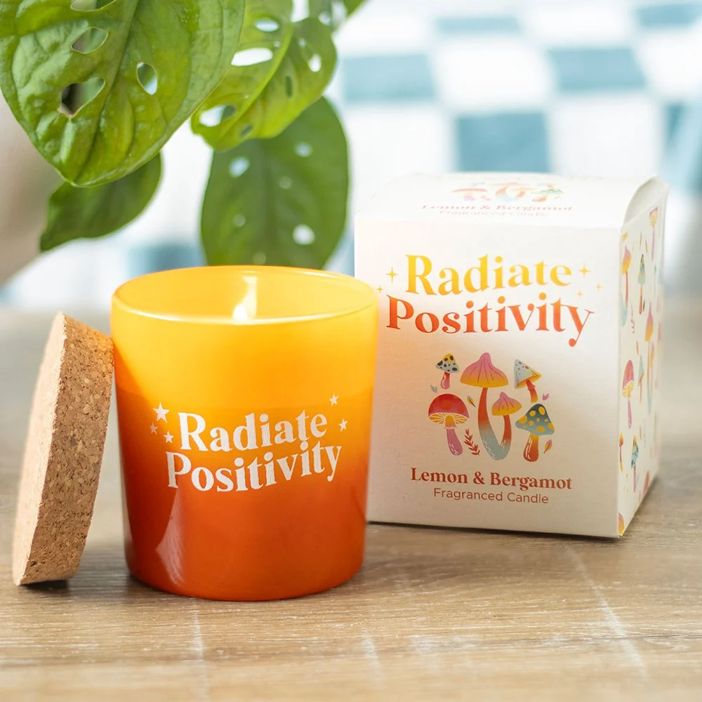 Vibrant yellow and orange glass pot with cork lid holding a lemon bergamot candle for fresh home fragrance