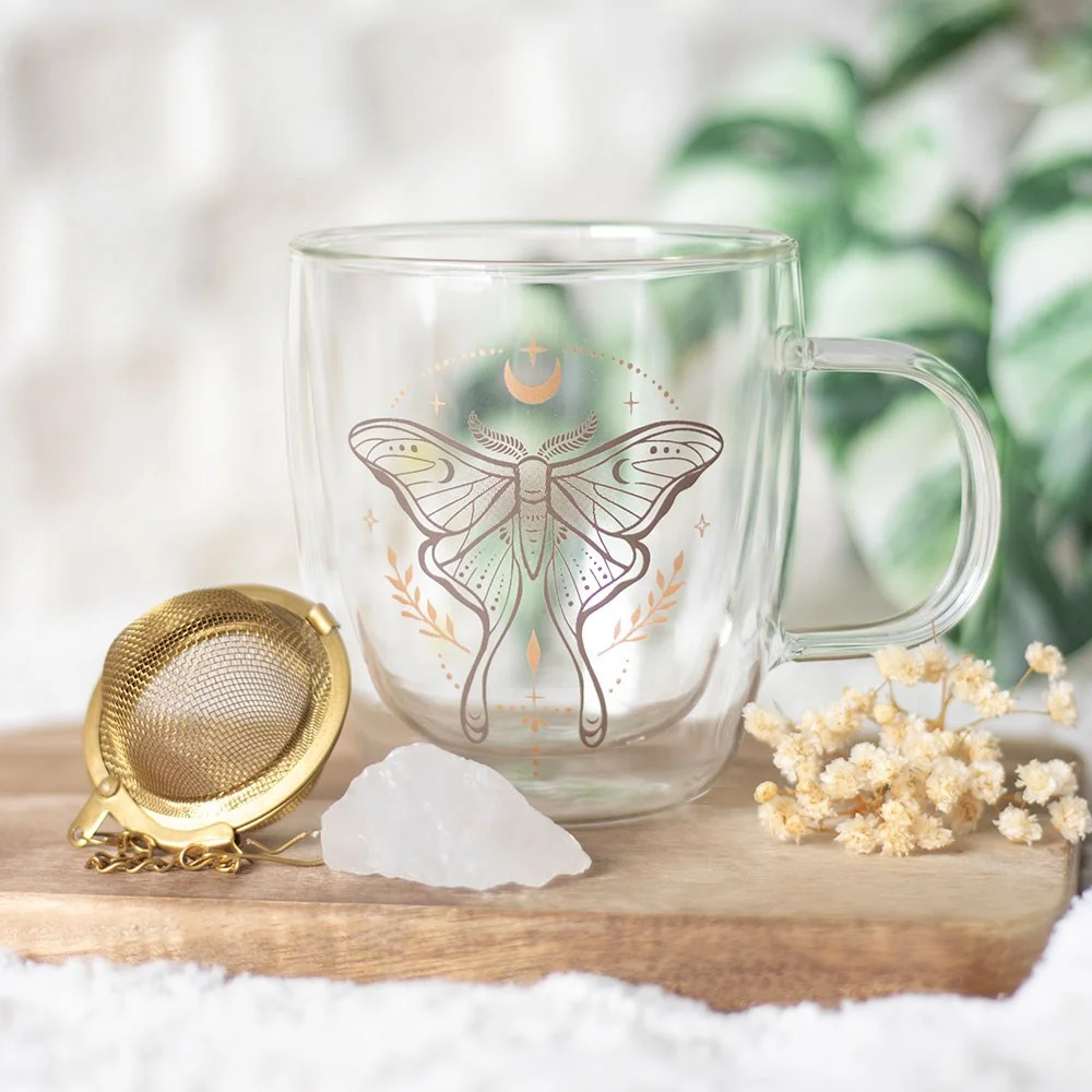 Clear double walled glass mug with luna moth design and quartz crystal tea infuser inside on white background