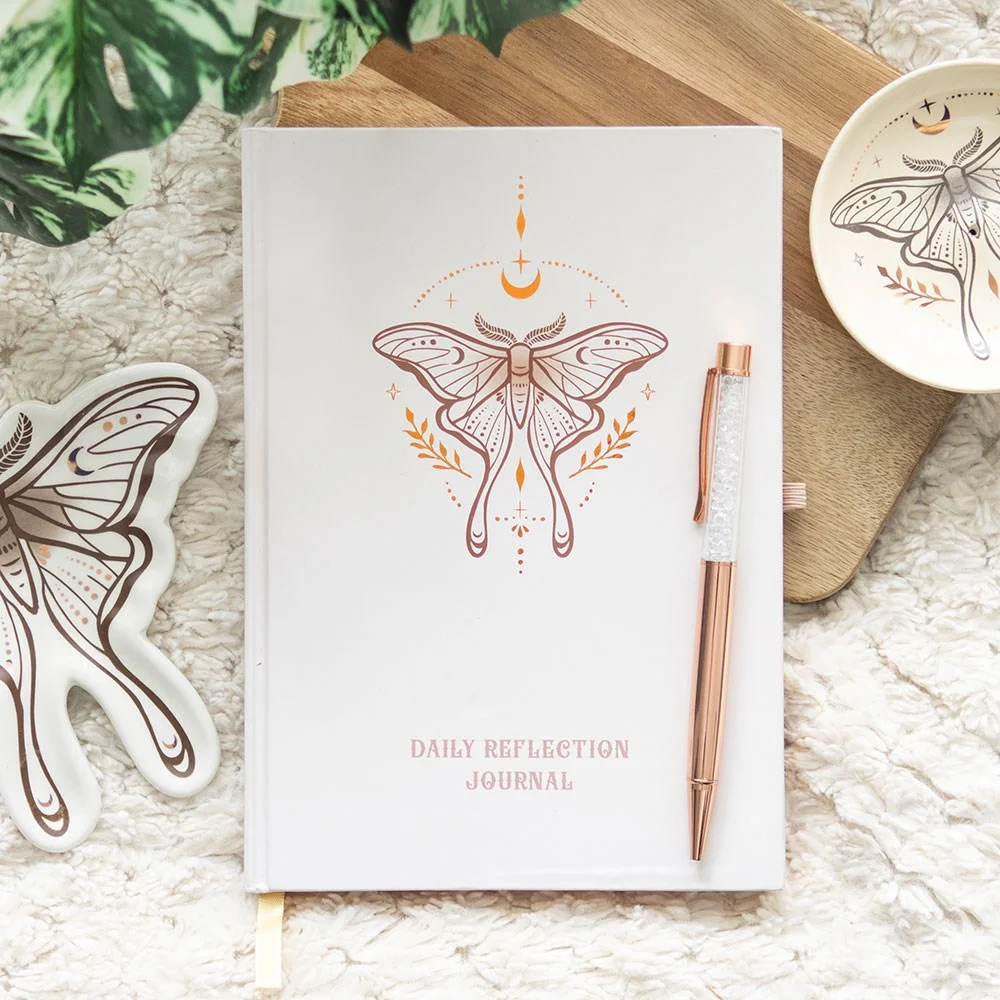 Luna moth design daily reflection journal open with clear quartz crystal pen on white background
