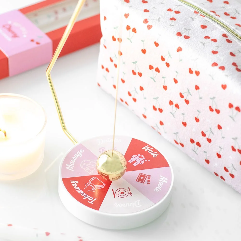 Gold-tone spherical pendulum swinging over a pink and red circular base with date night options on pendulum decision maker