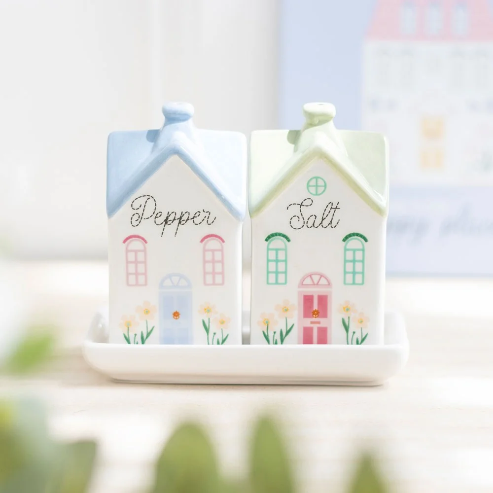 Pair of pastel salt shakers shaped like tiny town houses with floral accents, perfect for charming tableware.