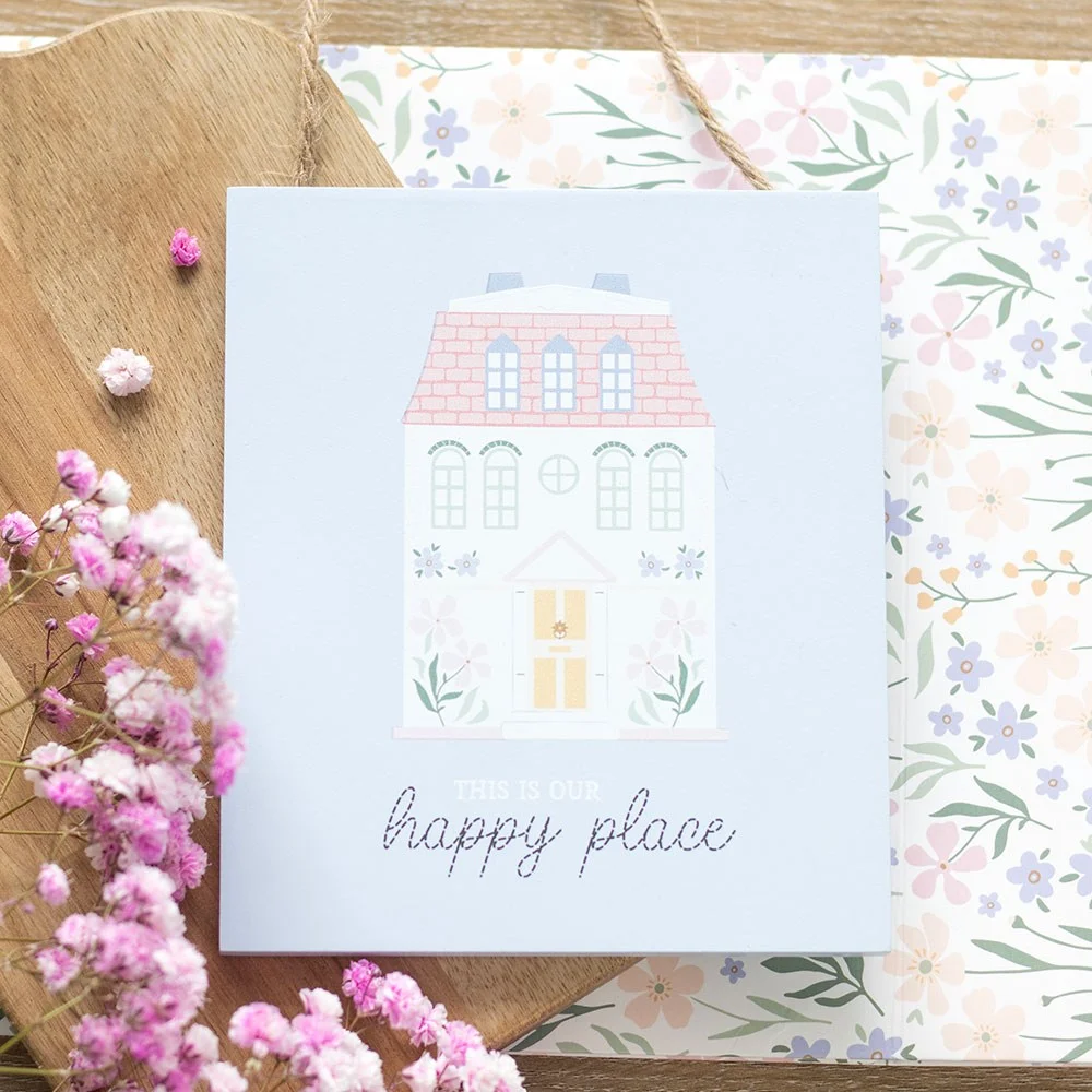 Pastel house-shaped happy place wall sign with "This Is Our Happy Place" text hanging on white background
