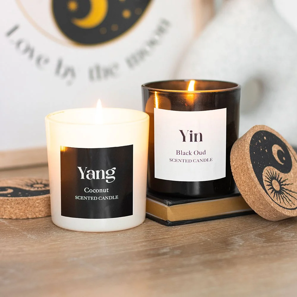 Set of 2 Yin Yang scented candles in black and white containers labeled Black Oud and Coconut on a white background