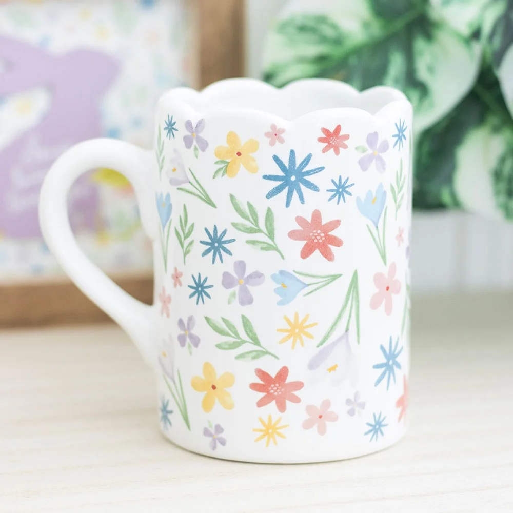Ceramic spring floral mug with pastel blooming flowers and scalloped rim on a white background