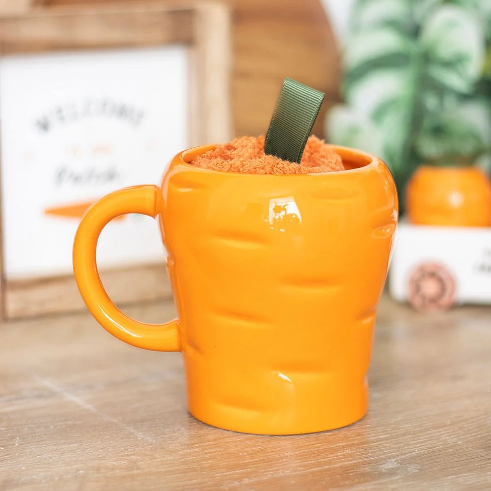 Bright orange carrot shaped mug with matching fluffy orange socks on a white background