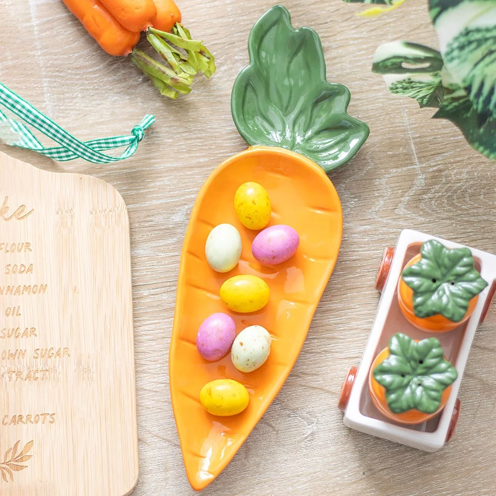 Bright orange carrot shaped serving dish on a white background, ideal for serving crudites or snacks at parties