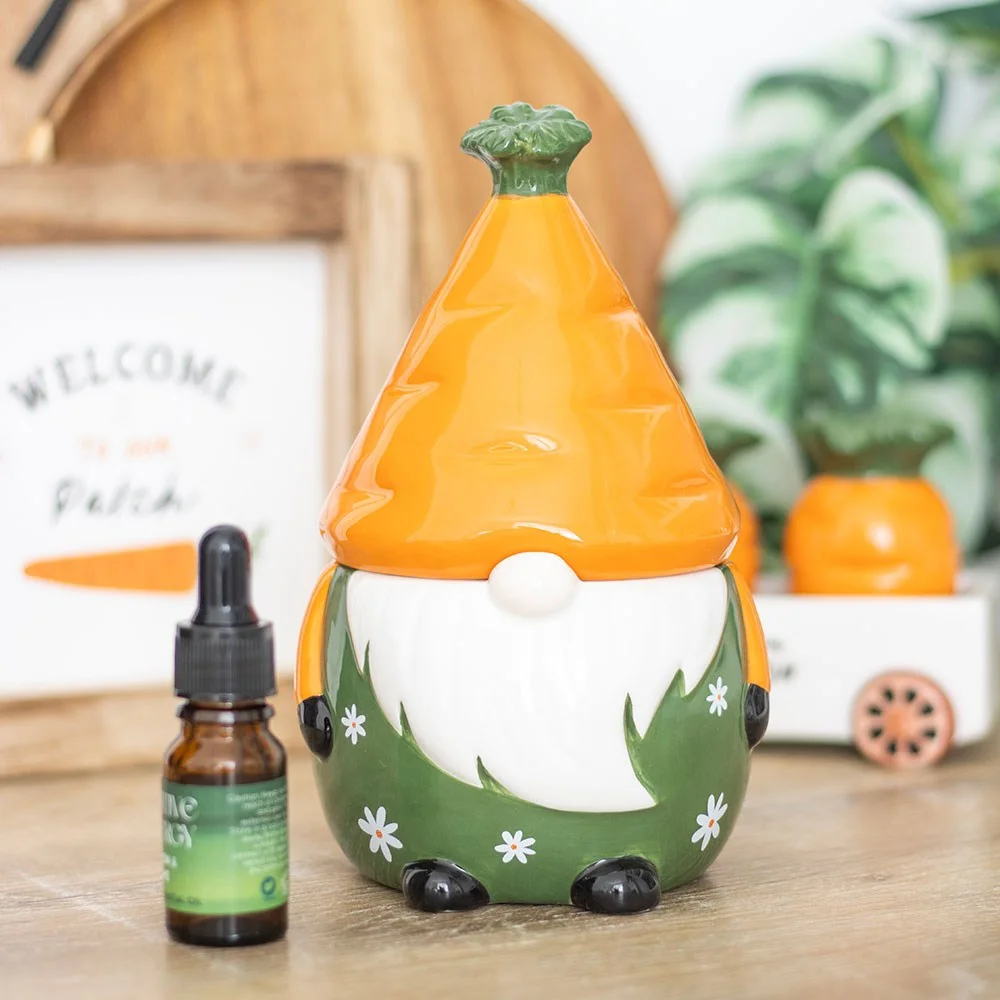 Ceramic gonk shaped carrot patch oil burner with removable carrot hat and lit tealight inside on white background