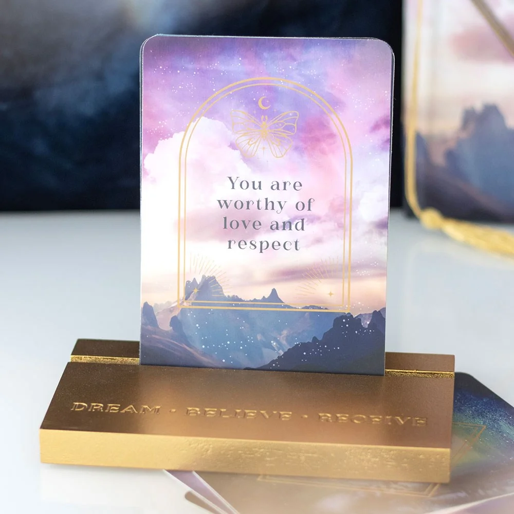 Ethereal sky-themed affirmation cards set with 10 inspiring messages displayed on a wooden stand on a desk