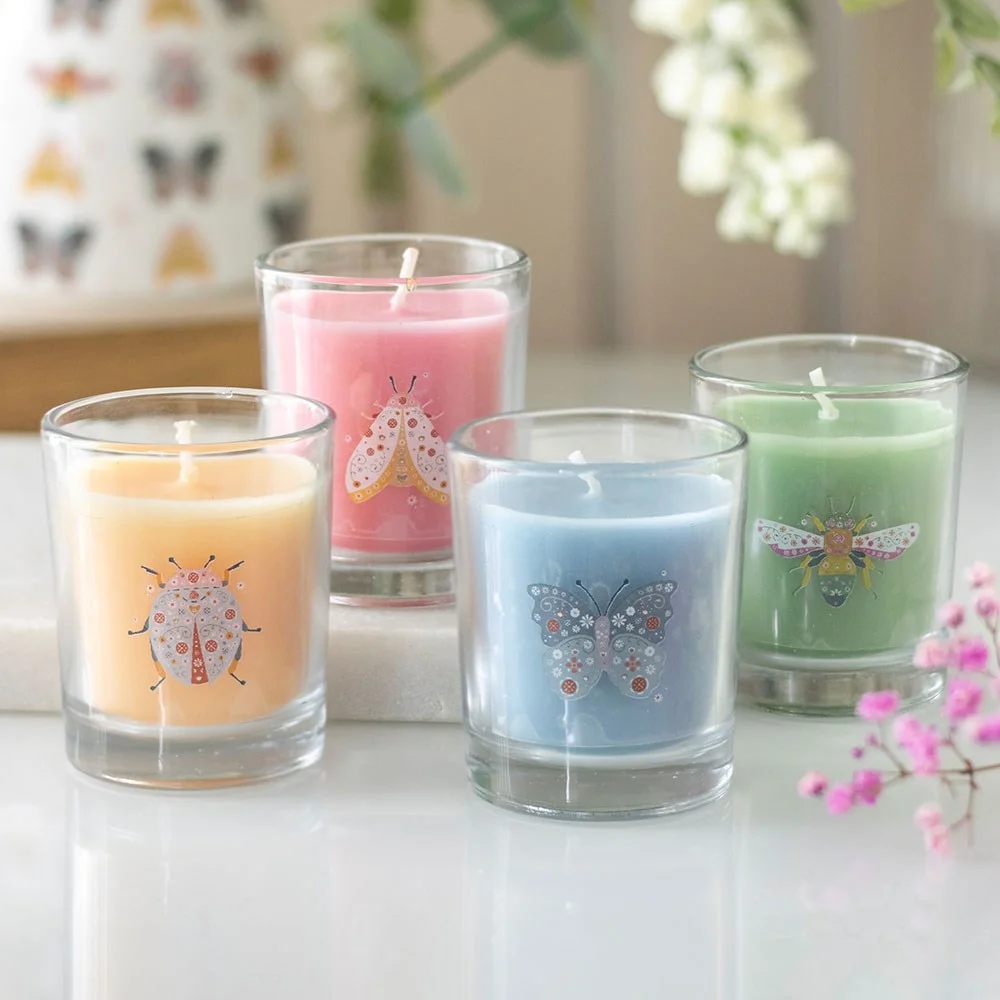 Set of 4 floral scented candles with pastel bug designs in green, pink, blue, and yellow, in a gift box