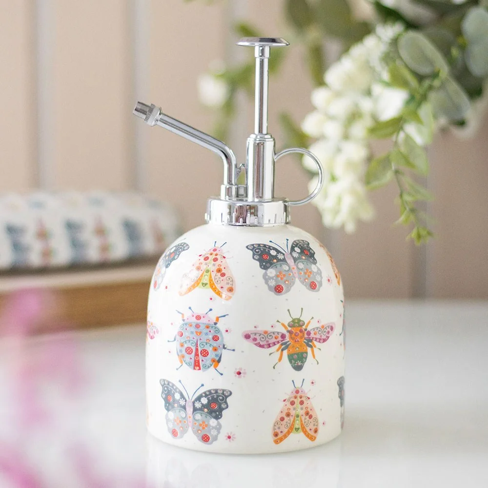 Ceramic plant mister with pastel floral bug design and silver plastic nozzle on a white background
