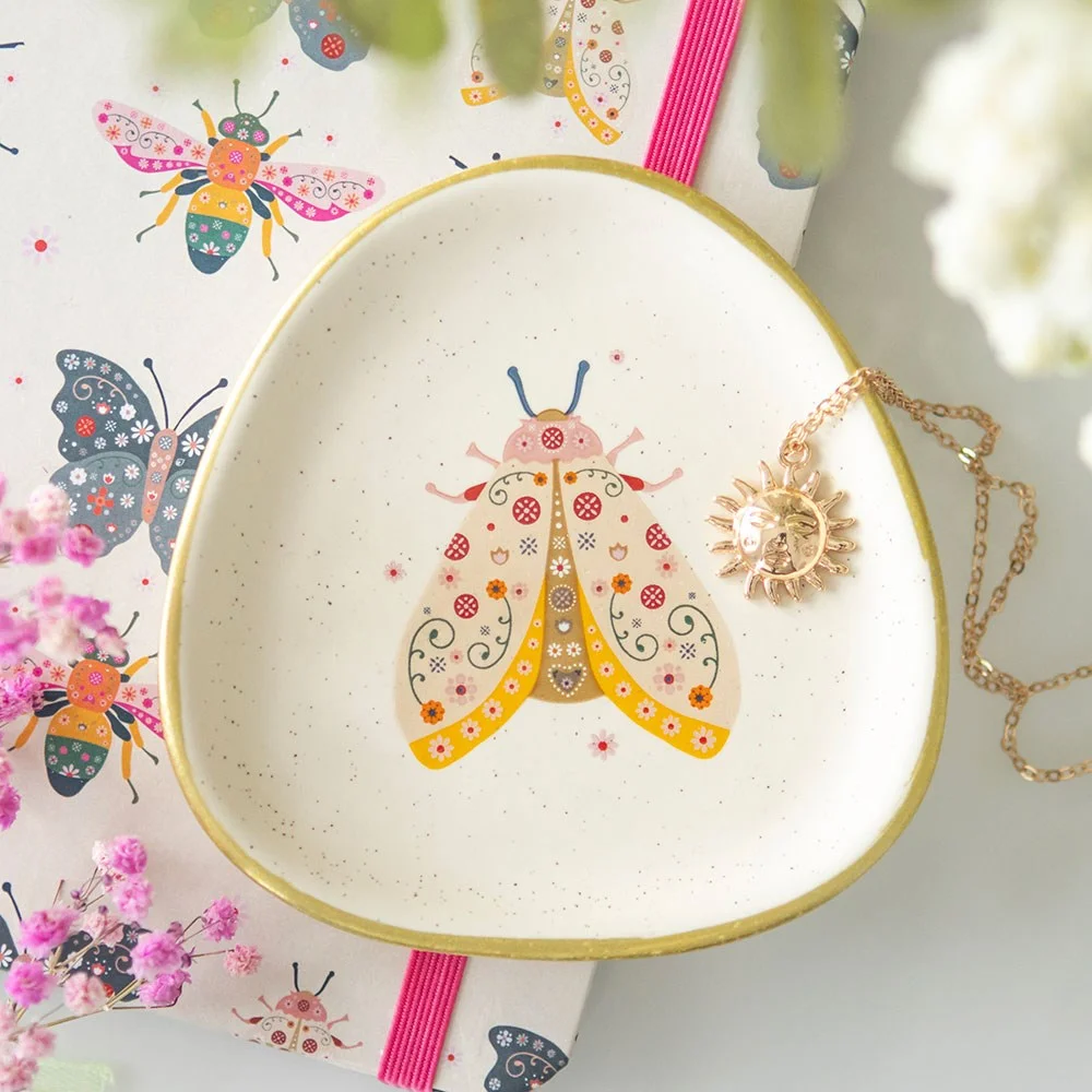 Floral moth trinket dish with speckled ceramic finish, gold edging, and playful floral moth design in organic shape