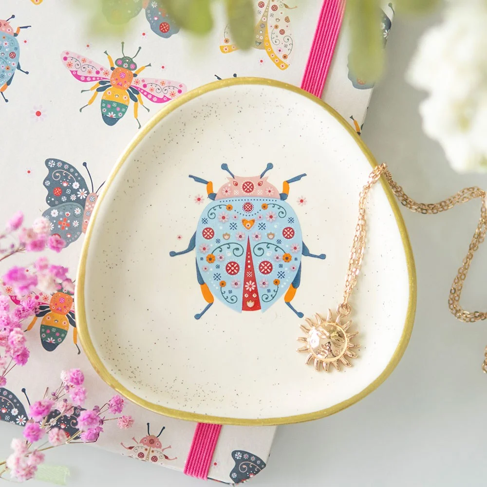 Floral ladybird trinket dish with speckled ceramic finish, gold edging, and playful ladybird floral design on organic shape