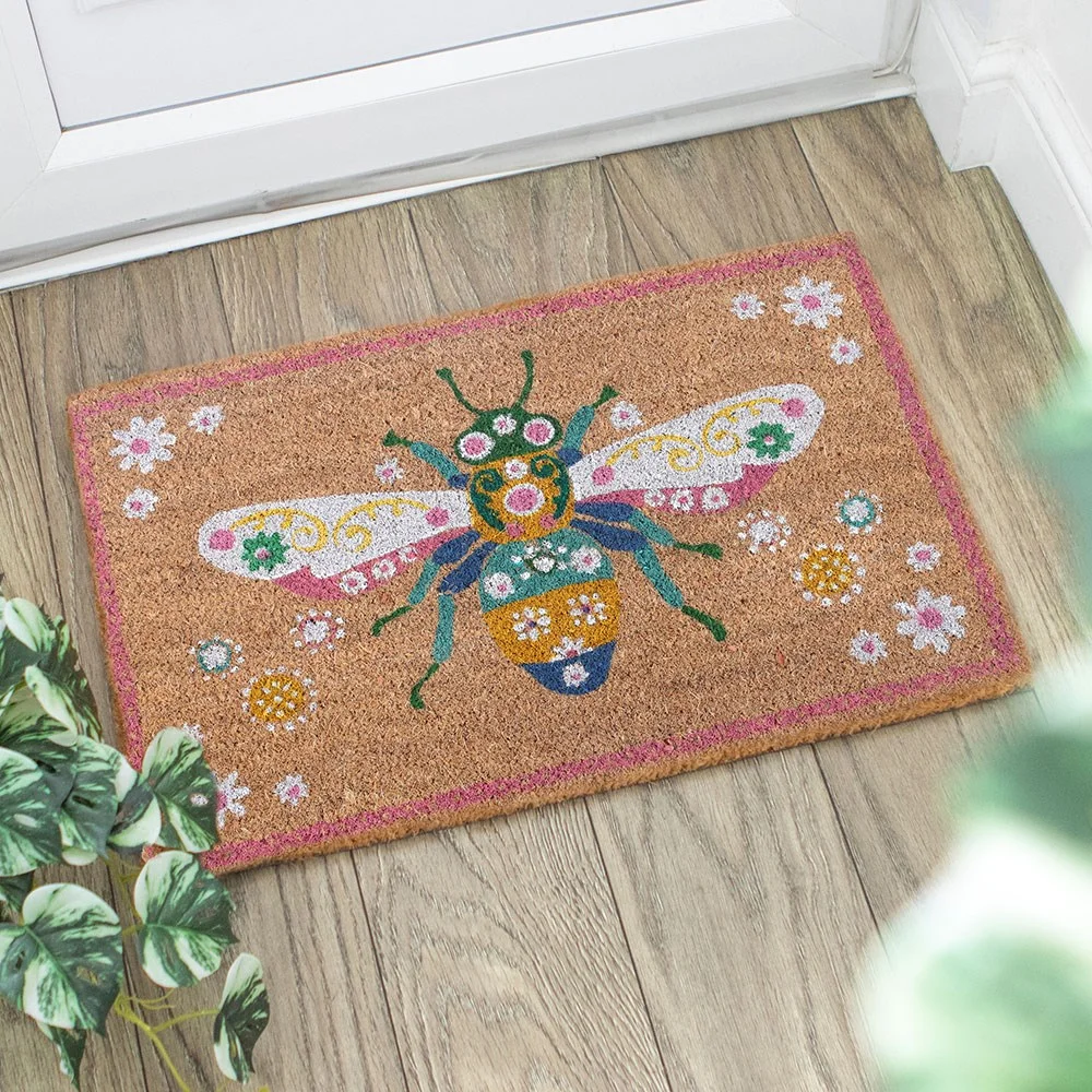 Floral bee doormat showing a detailed bee surrounded by blooming flowers on a coir mat
