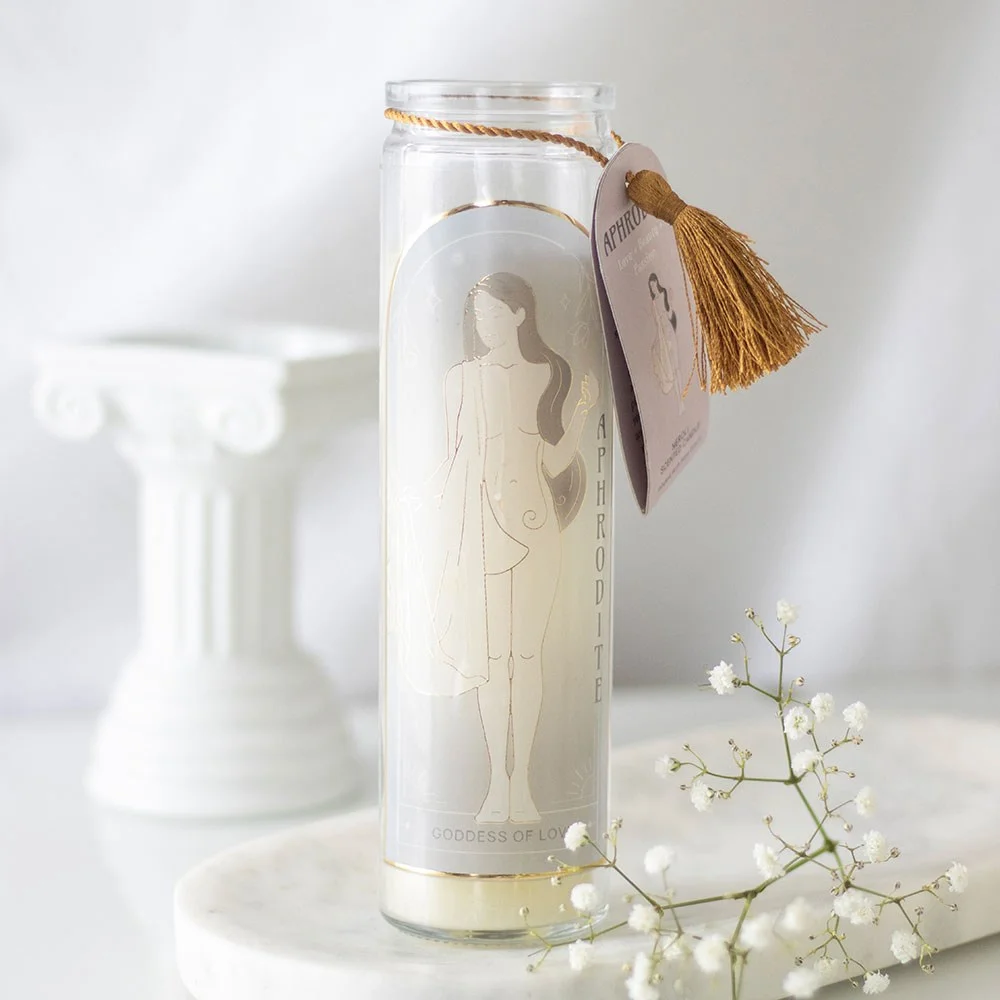 Aphrodite goddess candle in a glass tube with rose quartz crystals and elegant label on a white background