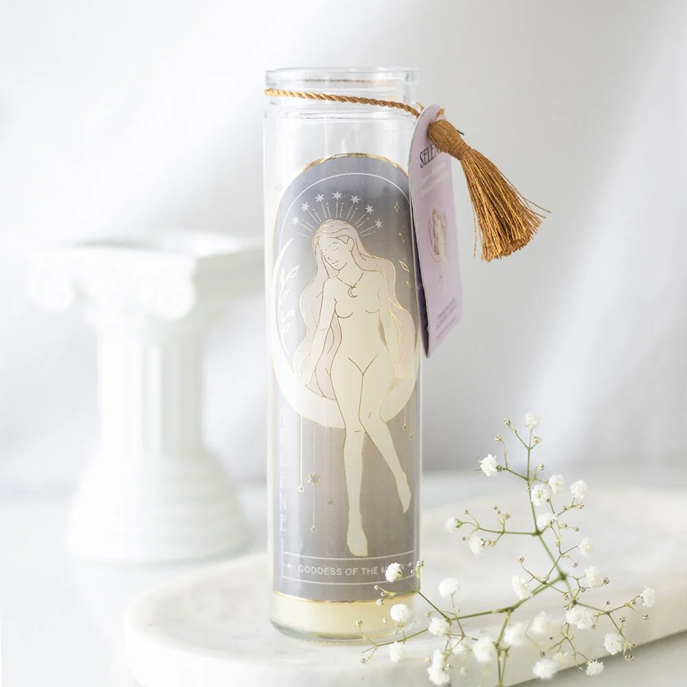 Selene goddess tube candle with amethyst crystals in clear glass jar, lit with soft flame on white background
