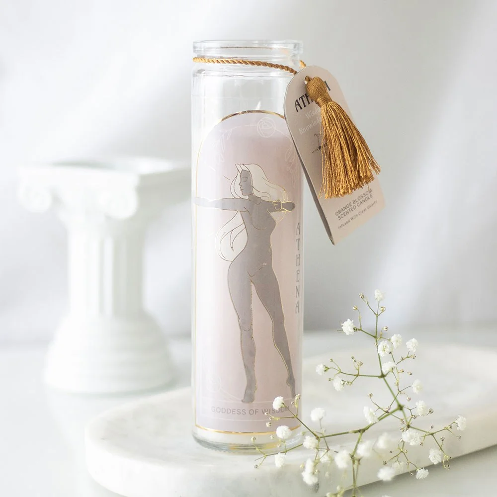 Athena goddess candle in a clear glass jar with quartz crystals, lit with soft orange blossom scent, on white background